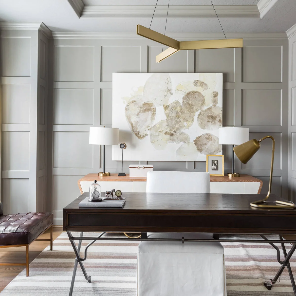 Gray wall grid behind a large pale abstract artwork and dark office desk