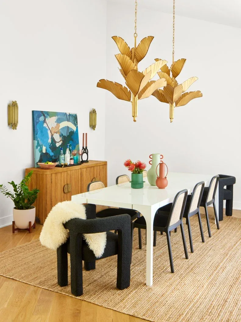 Wood ribbed dining sideboard with round gold pulls beneath teal artwork and two gold wall lights