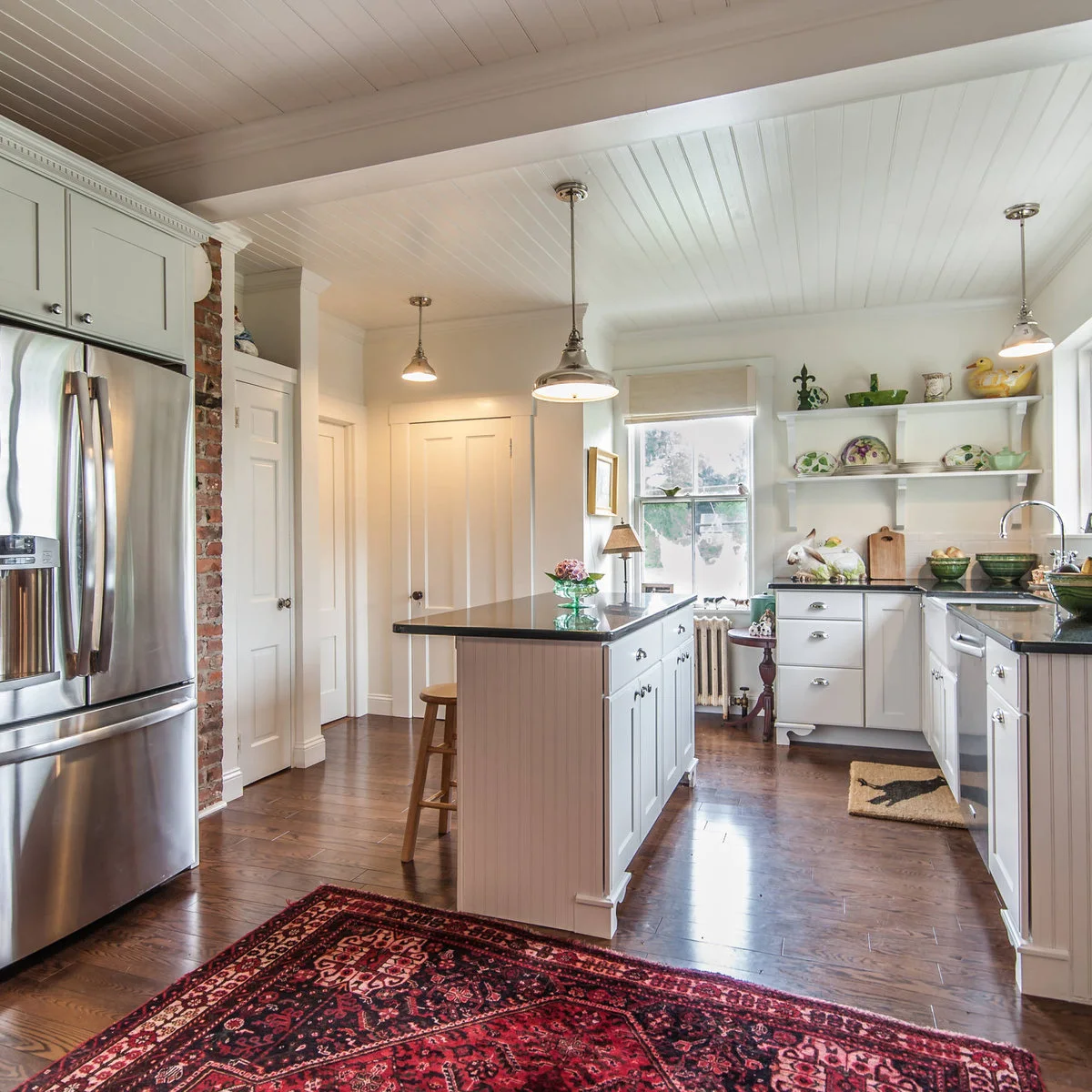 White grooved ceiling above a pale kitchen island and open display shelves