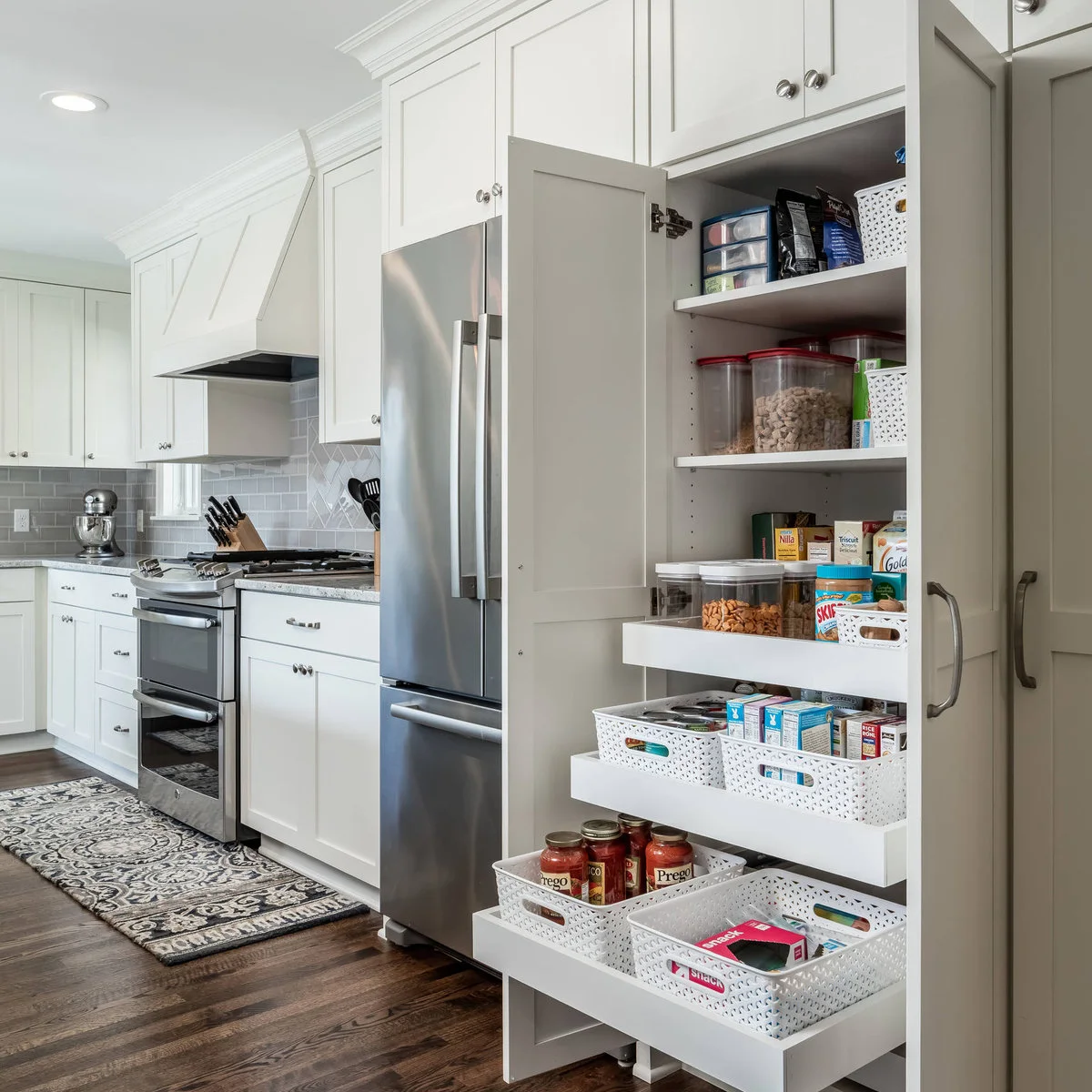 Tall white kitchen pantry cabinet with pull-out trays and grouped food containers