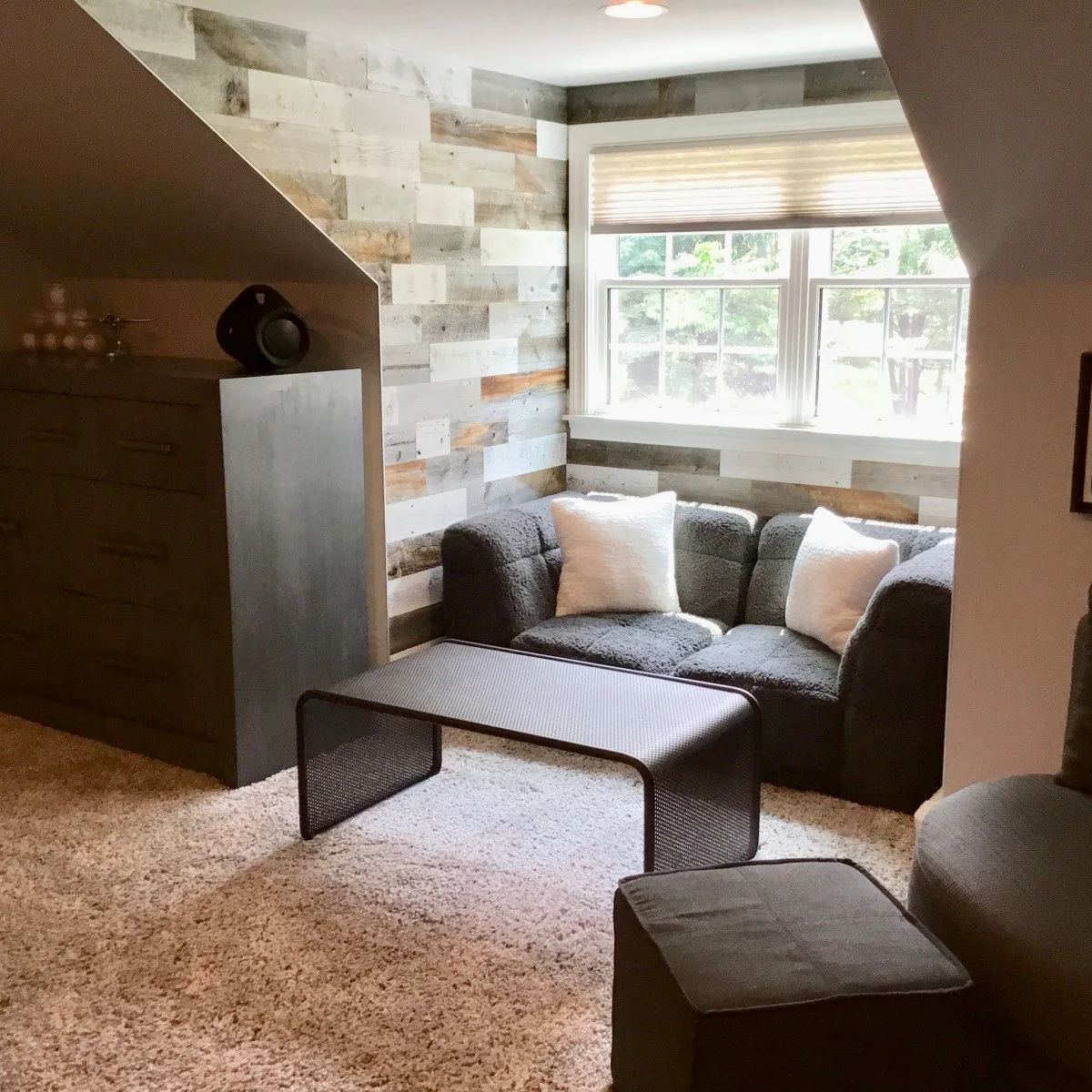 Teen room sitting alcove with two gray chairs, a low dark table and pale plank-effect wall