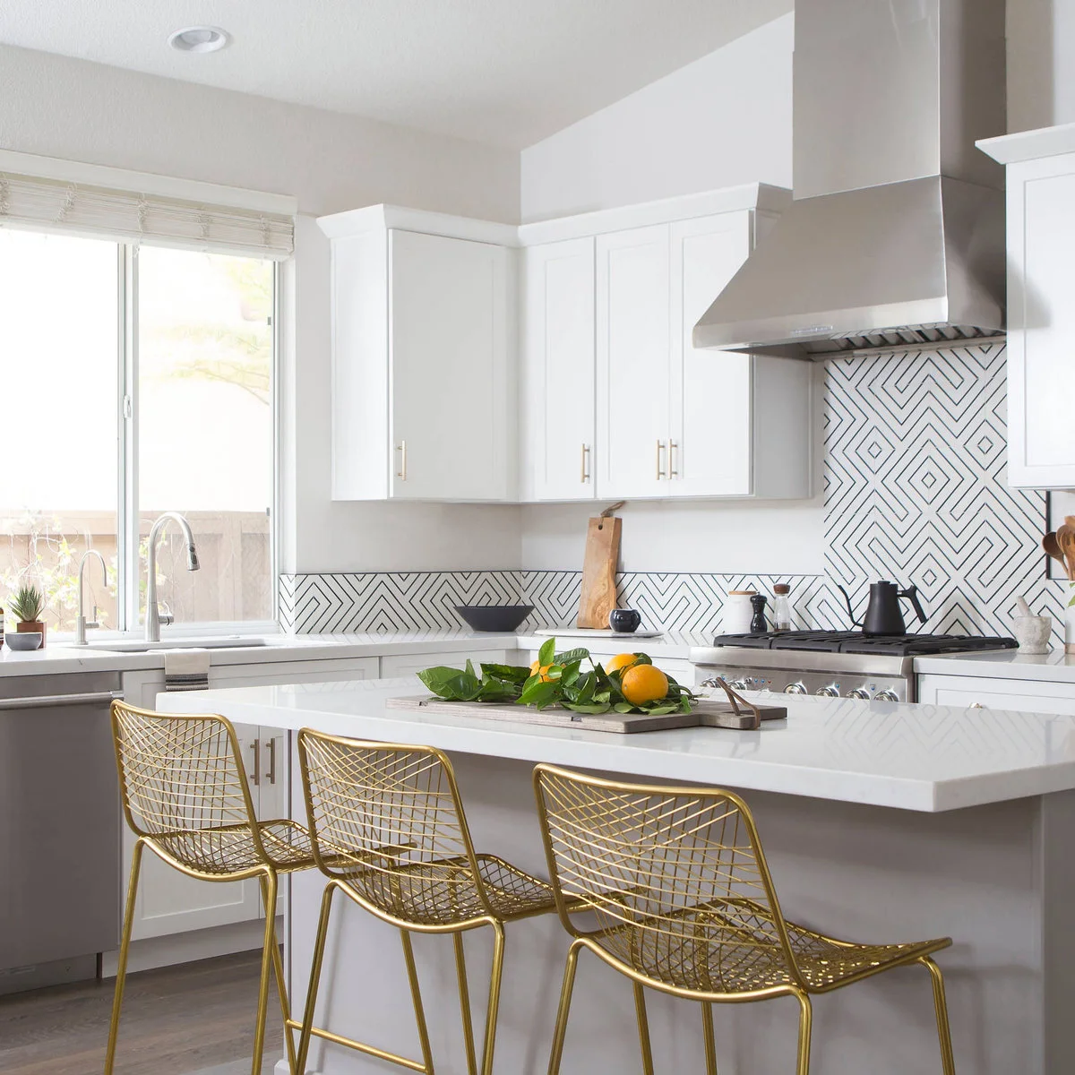 Gold-colored wire kitchen stools with open mesh seats and backs beside a white island