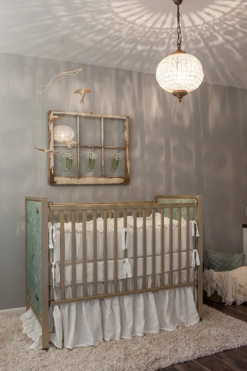 Muted gray nursery with open-frame crib, rustic window-frame mirror, pendant and pale rug