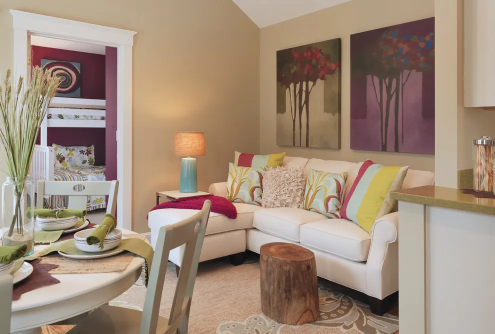 Two colorful canvases hang above a small pale sofa in a compact living area