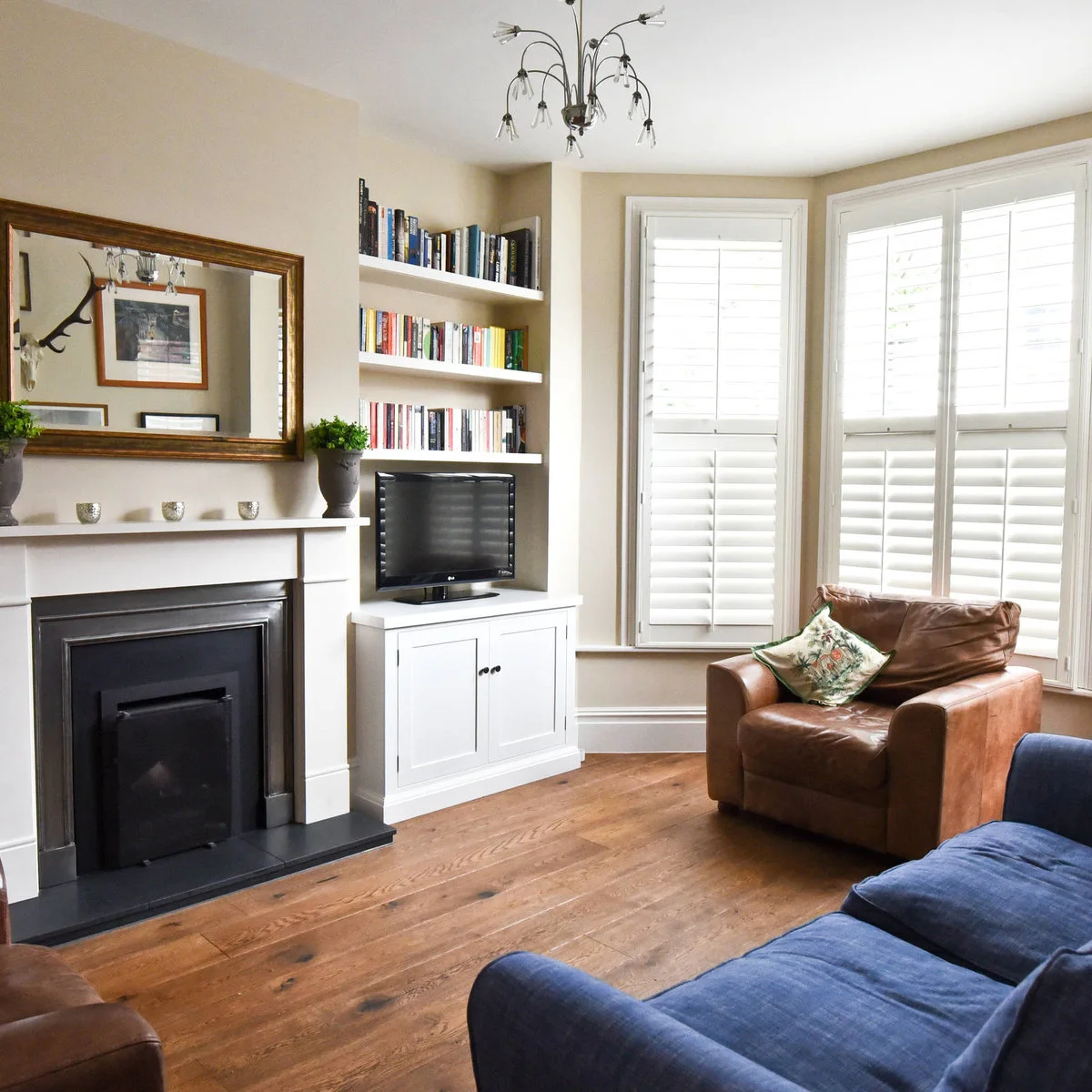 Victorian front room with white alcove shelves, a low television cabinet and brown armchair