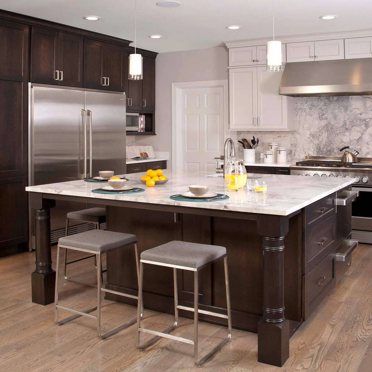 Two gray upholstered backless stools with slim metal sled frames beside a dark wood island