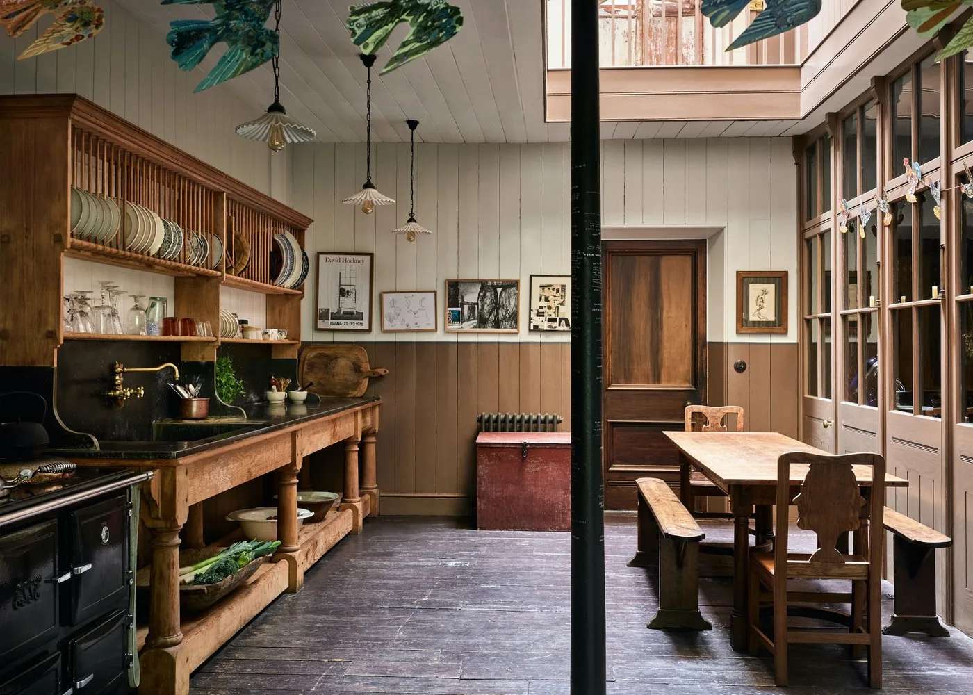 Kitchen with a large wood plate dresser, brown lower wall paneling, a small table and glazed partition.