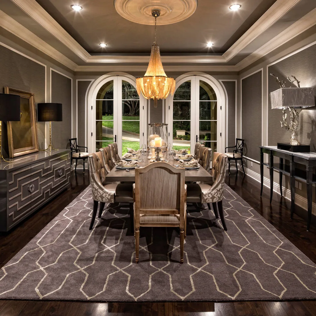 Large gray rug with pale angular outlines beneath a formal dining table and upholstered wood chairs