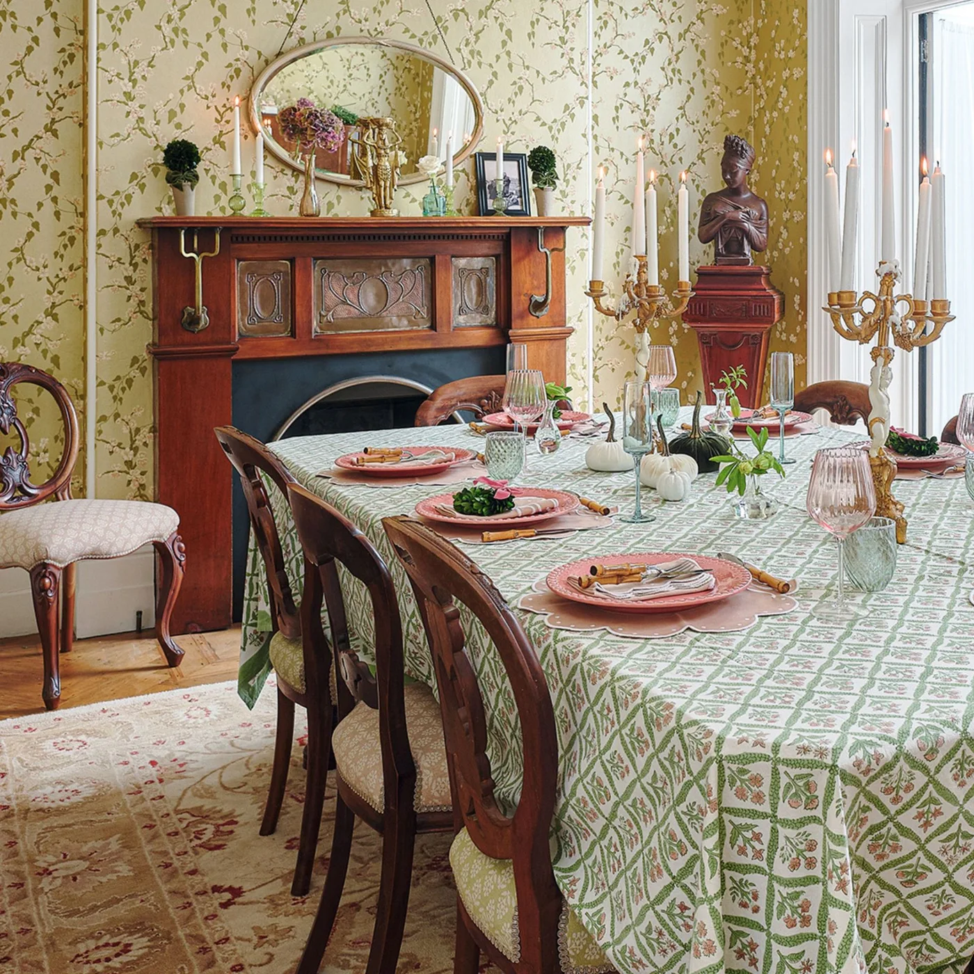 A timber dining-room fireplace has patterned metal panels and curved metal details beneath an oval mirror.