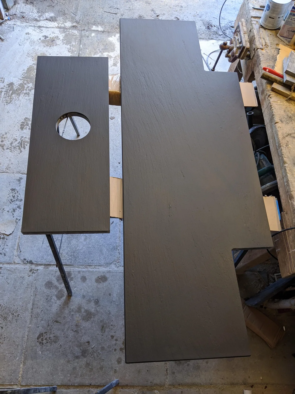 Two uninstalled riven slate hearth sections lie side by side, with a circular opening cut into the narrower rear section.