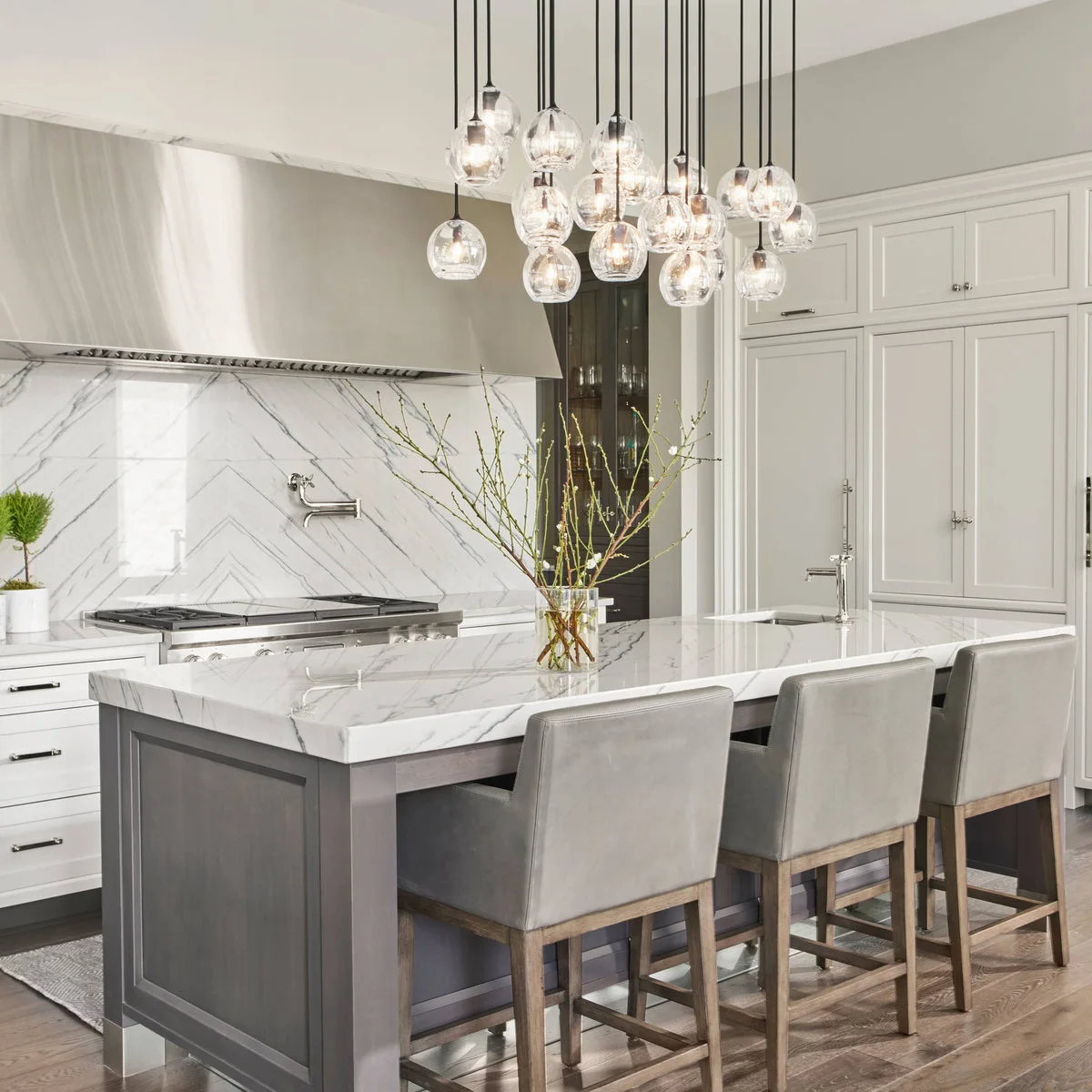 White inset cupboards with visible hinges sit above integrated refrigeration beside a gray kitchen island.