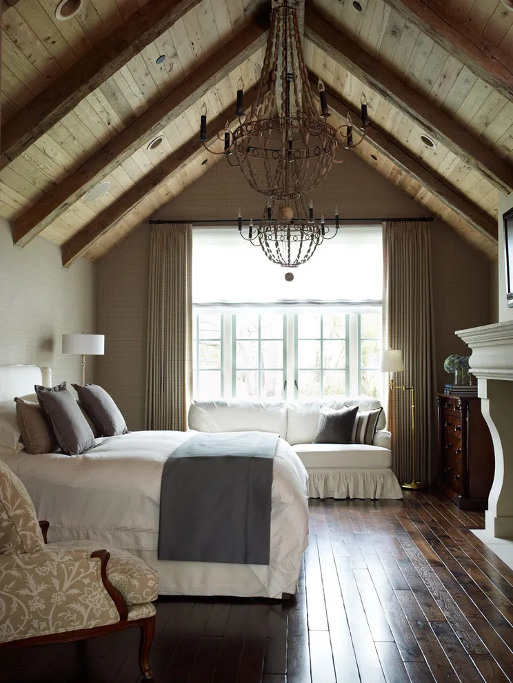 Dark wood flooring sits beneath exposed timber roof framing and pale bedroom furniture