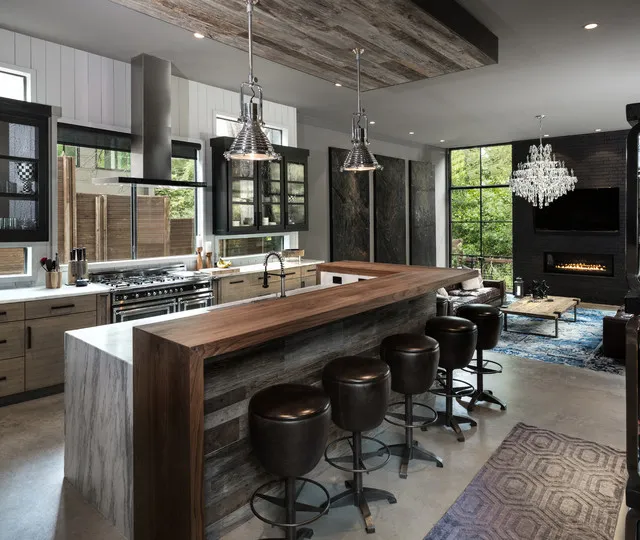 Black glazed upper cupboards flank a kitchen window above timber base cabinets, a wood-topped island and black stools.