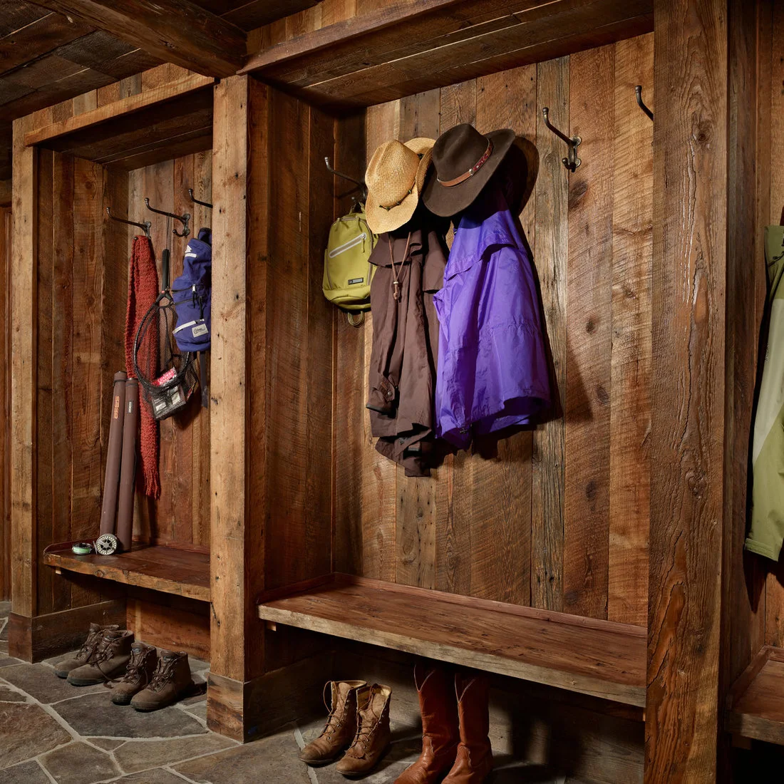 Rustic timber coat bays with dark hooks, built in benches and boots below