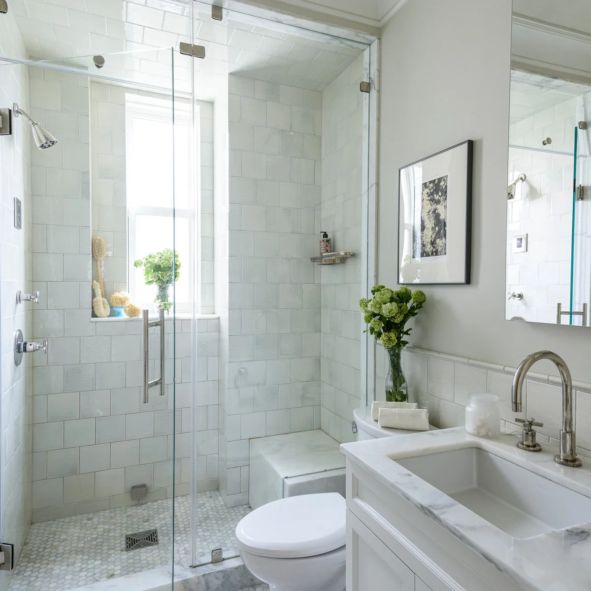 White tiled shower spanning a small bathroom behind a clear glass door
