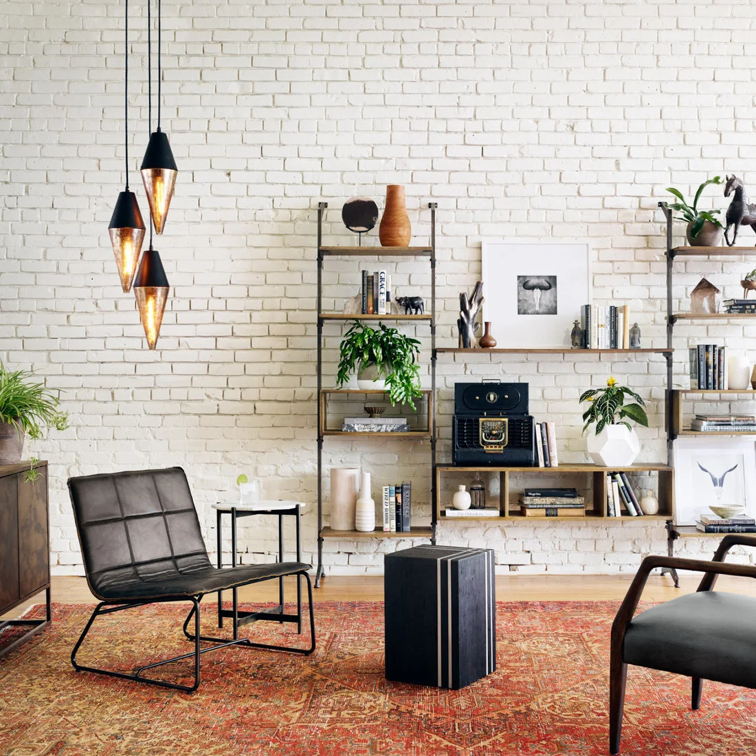 Dark framed chairs and open wood and metal shelves against white brick above a warm patterned rug