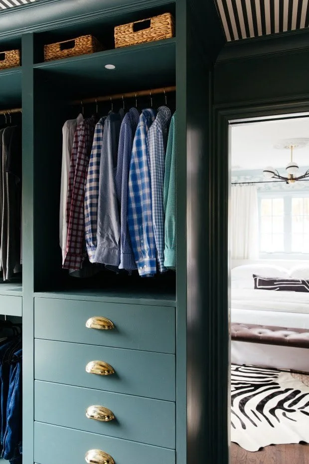 Blue-green PAX bay holding hanging shirts over drawers with shell-shaped gold-colored pulls