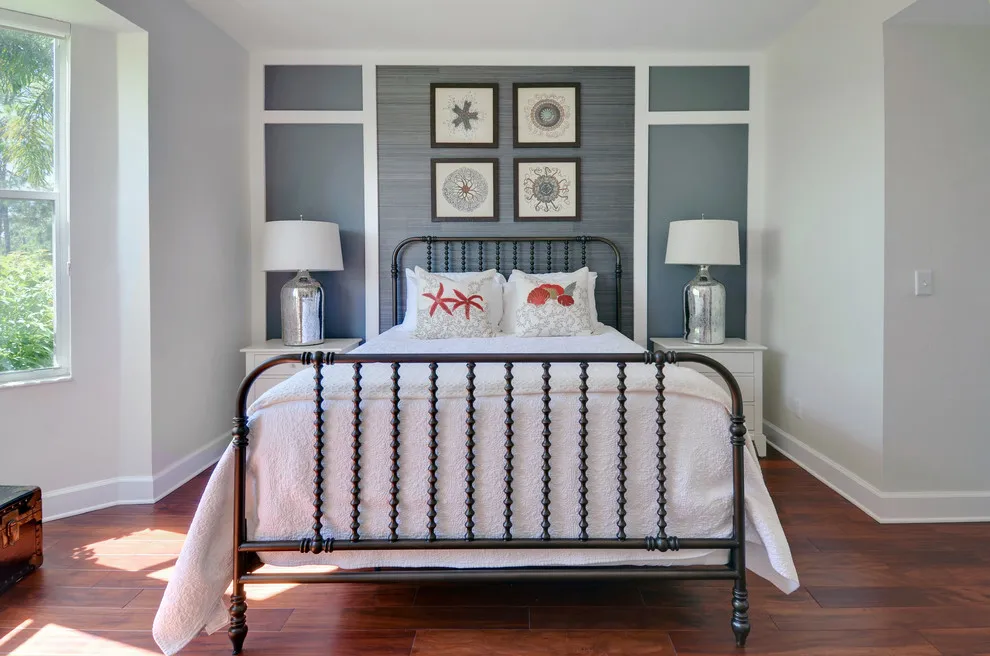 A muted green-gray paneled wall sits behind a black metal bed and a small picture grid