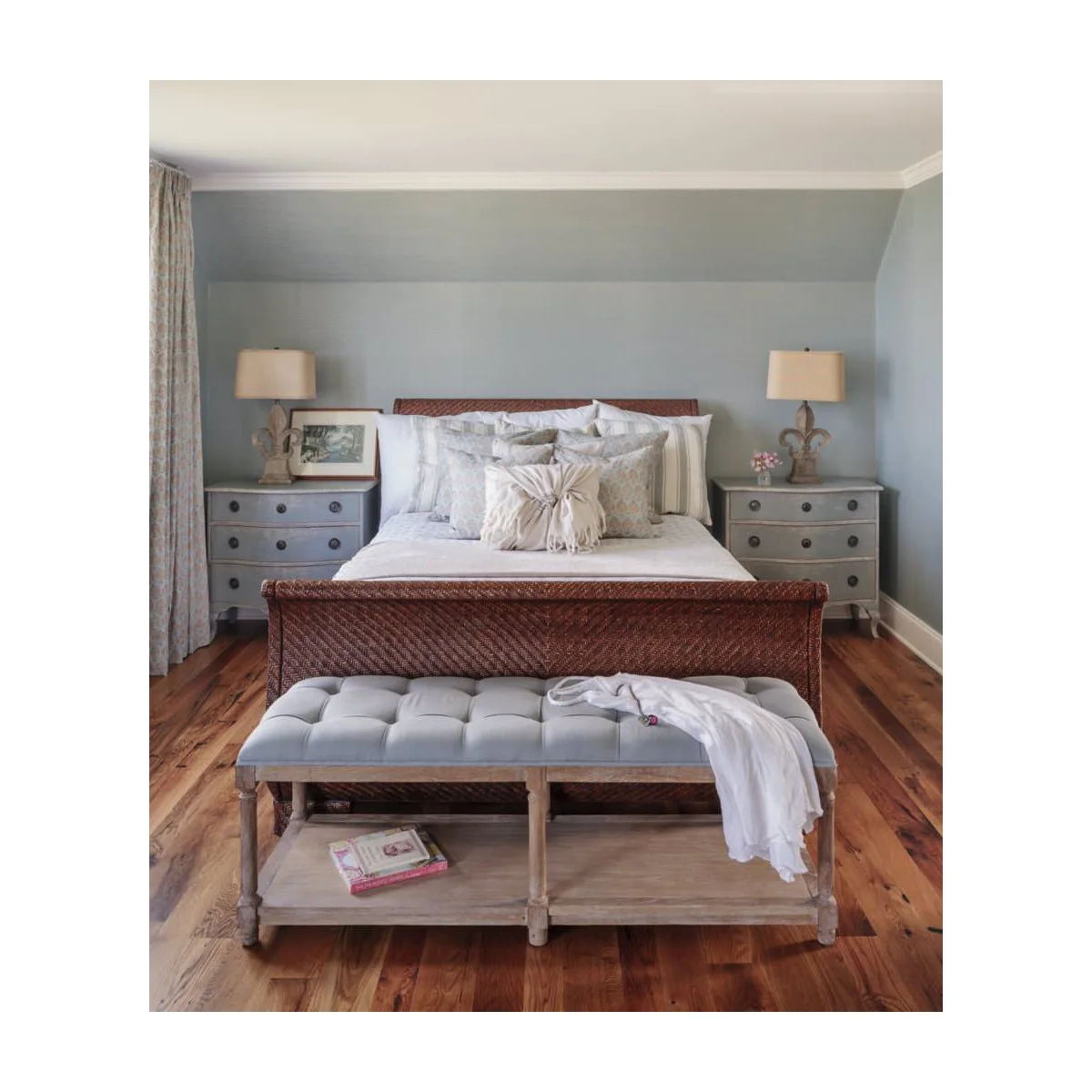 Pale tufted bedroom bench with wooden lower shelf in front of a woven bed frame