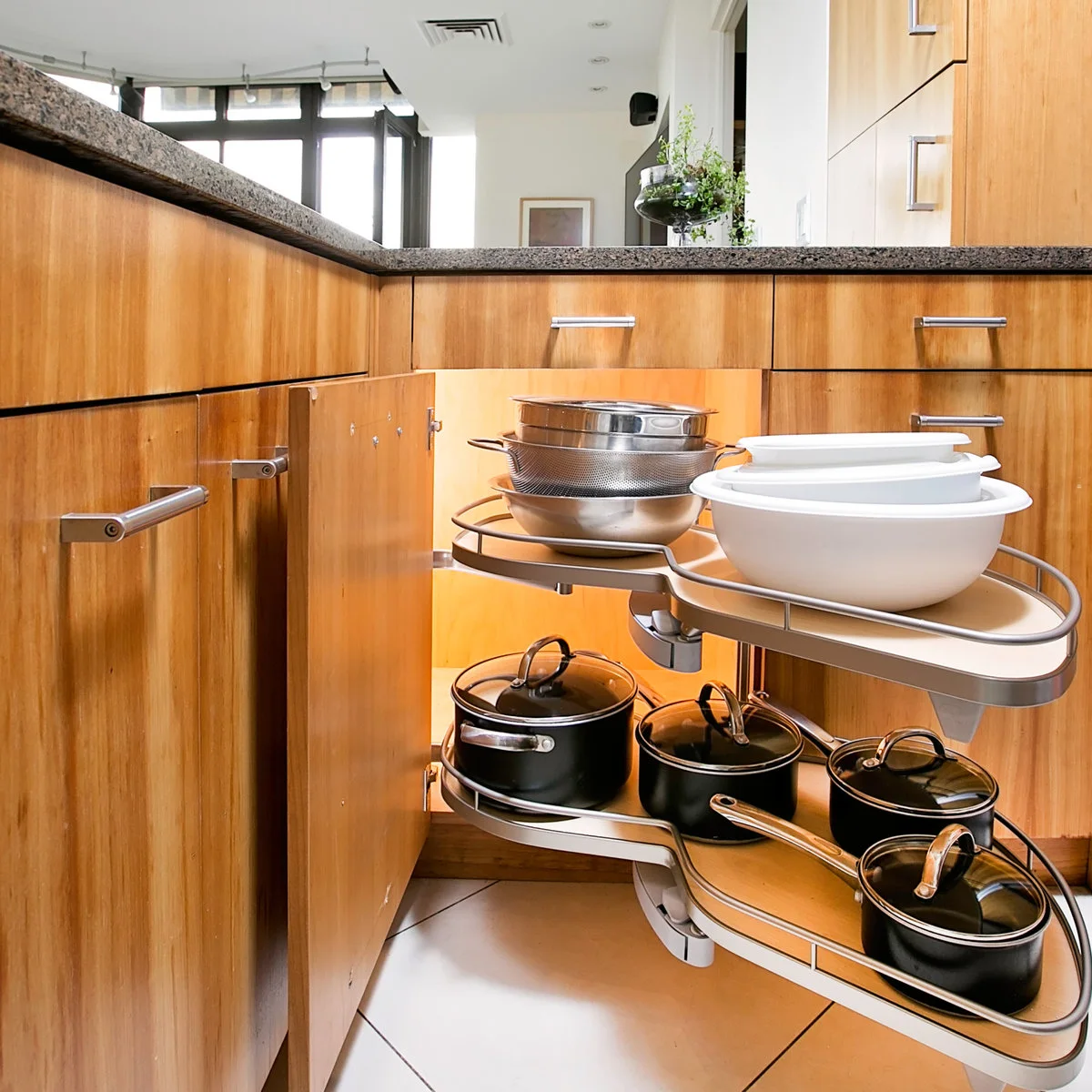 Wooden corner cupboard with swing-out shelves of nested bowls above lidded pans