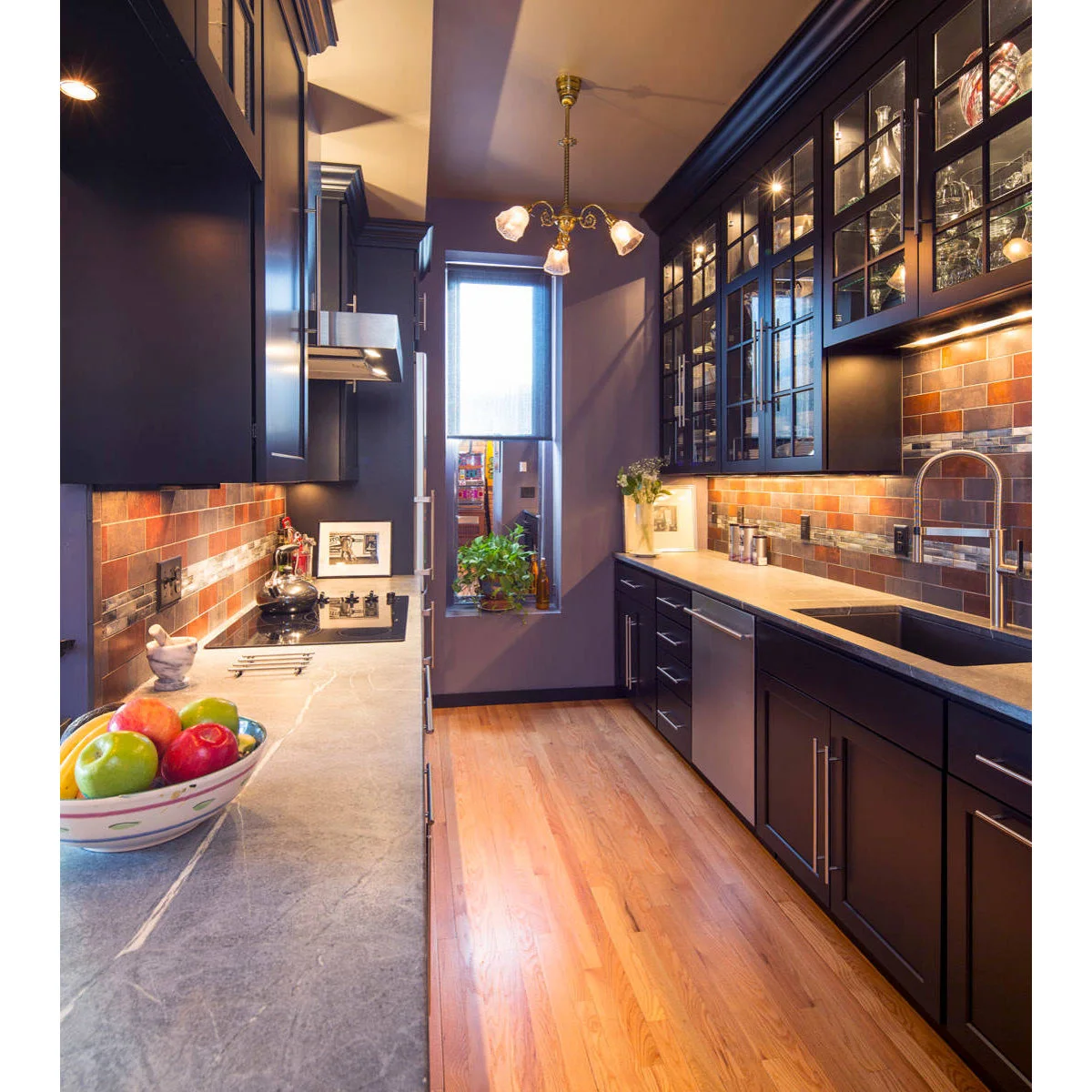 Dark galley kitchen with glazed upper cupboards, warm-toned tile and under-cabinet lighting