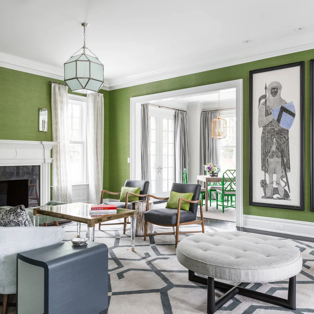 Green living room walls surround charcoal chairs, a pale gray ottoman and a gray geometric rug.