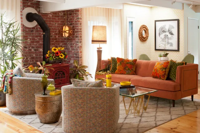 An orange sofa faces textured pale chairs beside brickwork and a small table.