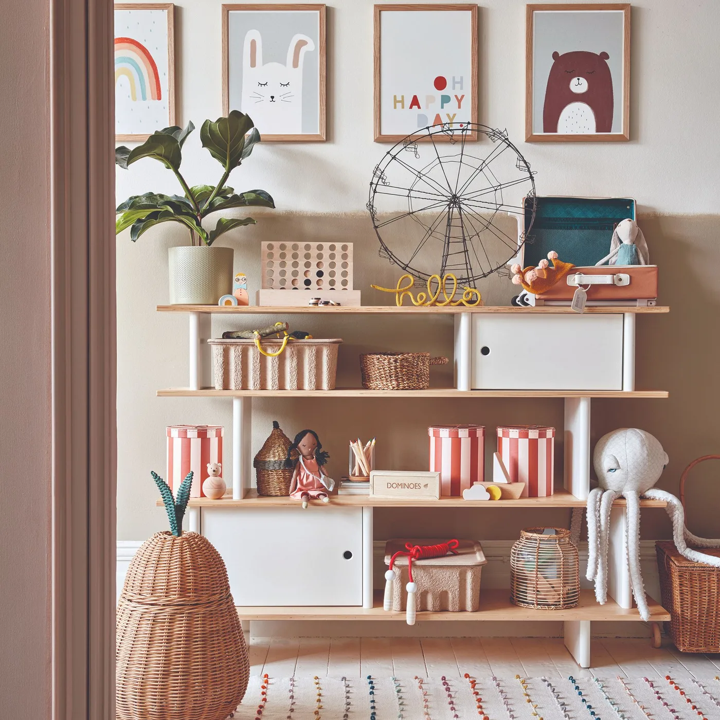 Wooden nursery shelves with woven baskets, books, decorative objects, closed white compartments and illustrated framed prints.