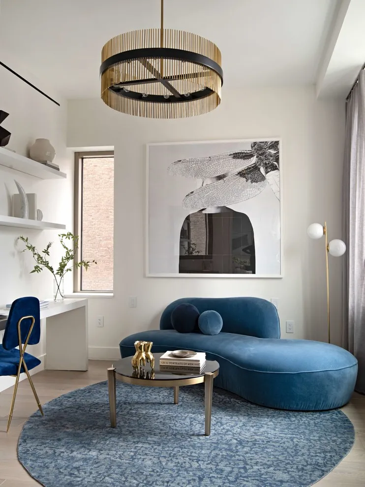 A black-and-white abstract picture hangs above a rounded blue sofa