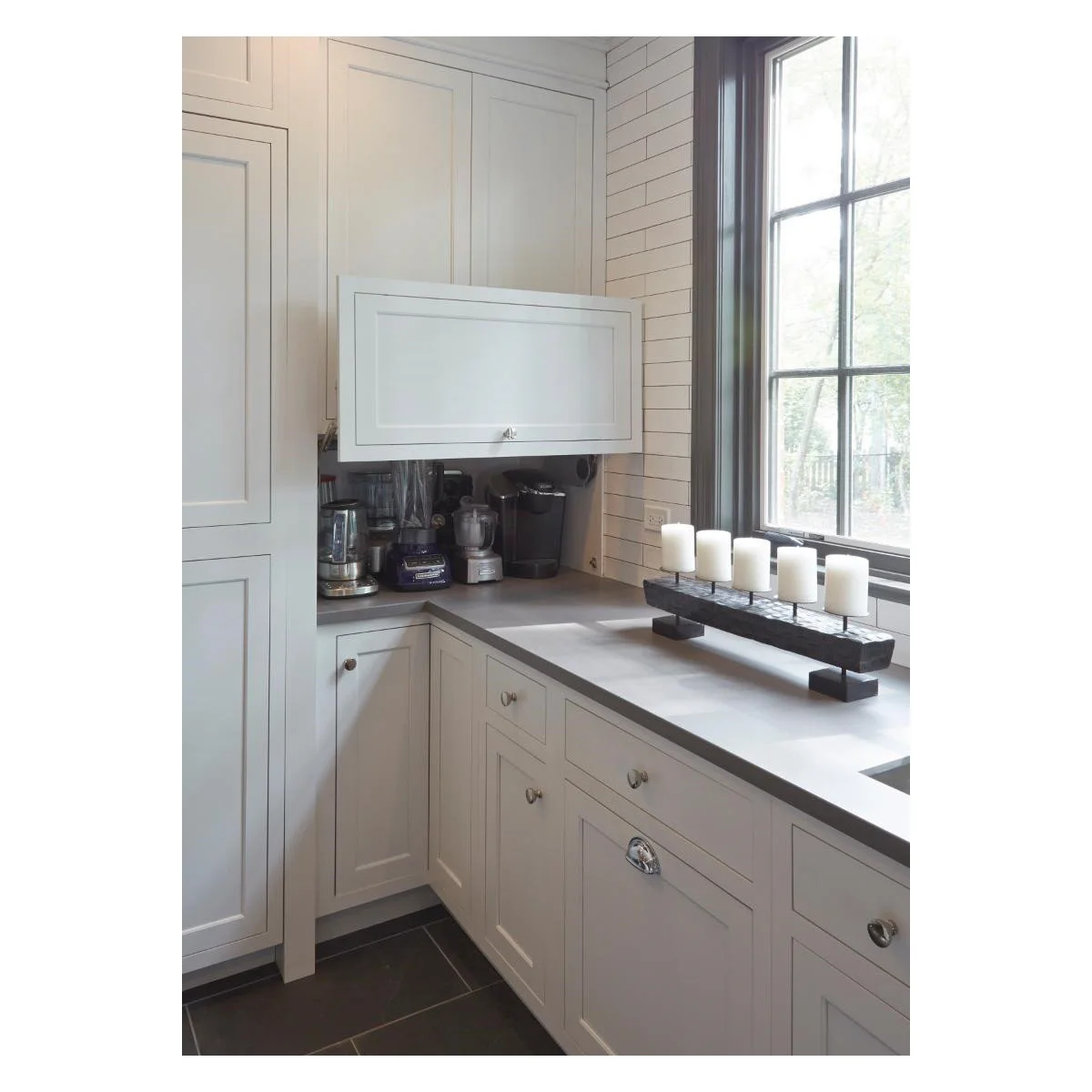 White corner appliance cupboard with raised door above several small kitchen appliances