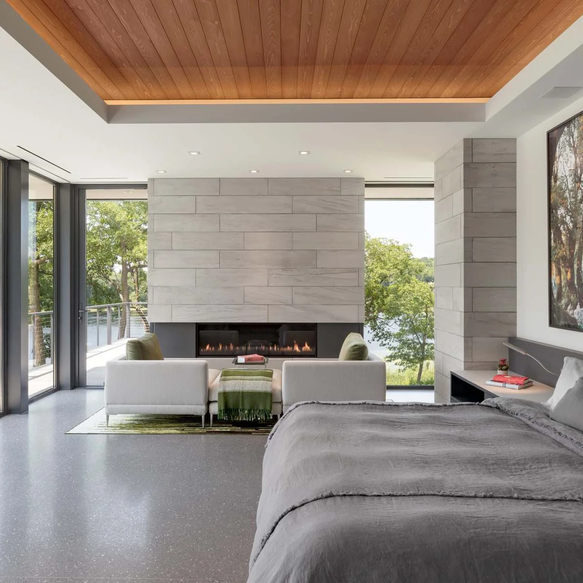 Wood-paneled ceiling inset above a pale bedroom with gray bedding and a fireplace seating area.