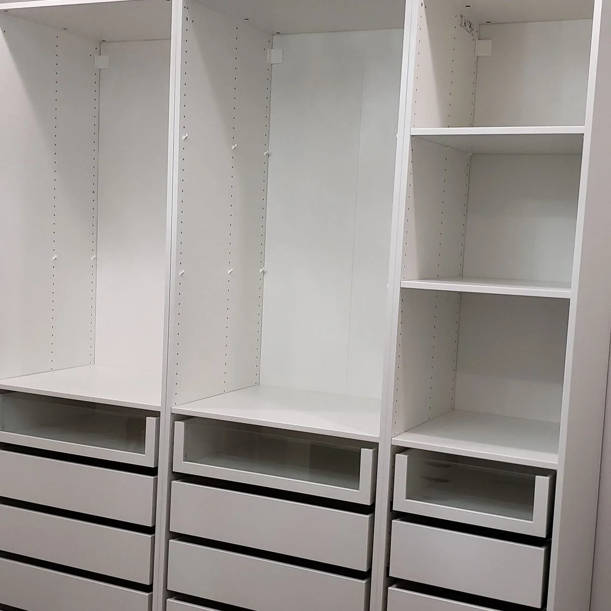 White PAX wardrobe interior with tall openings above glass-front and solid-front drawers