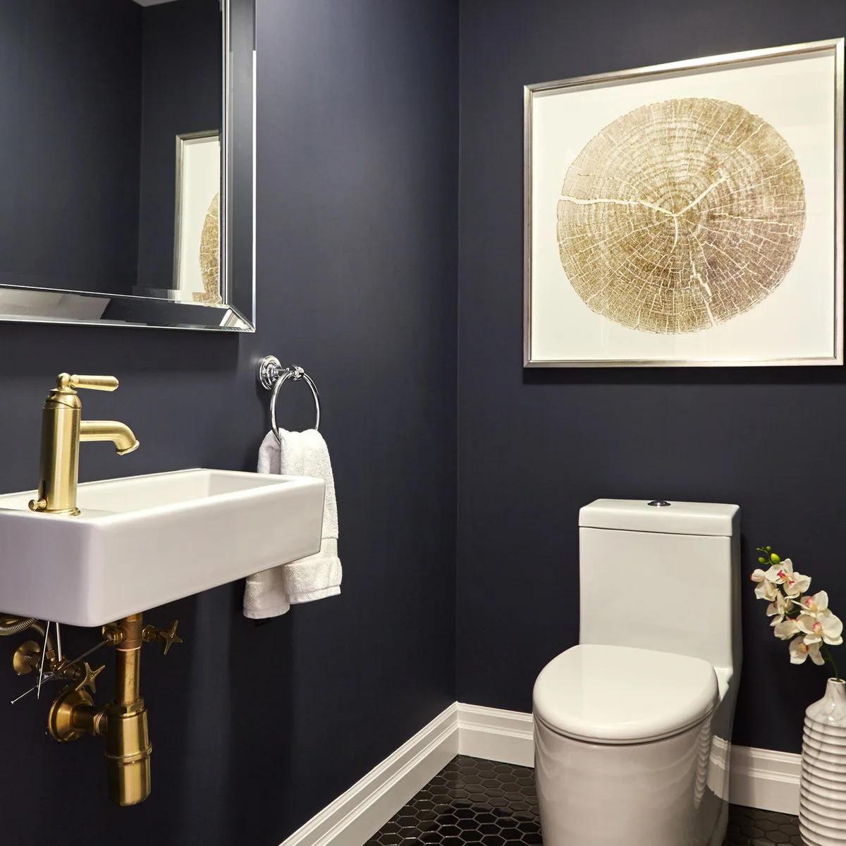 Pale tree-ring print above a toilet in a dark blue powder room