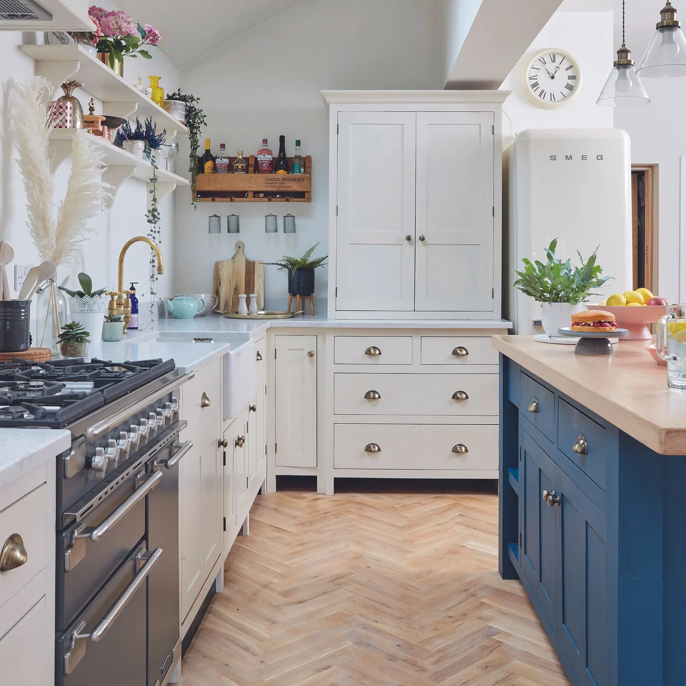 White framed cabinets include a tall countertop cupboard beside open shelves, a white refrigerator and a navy island.