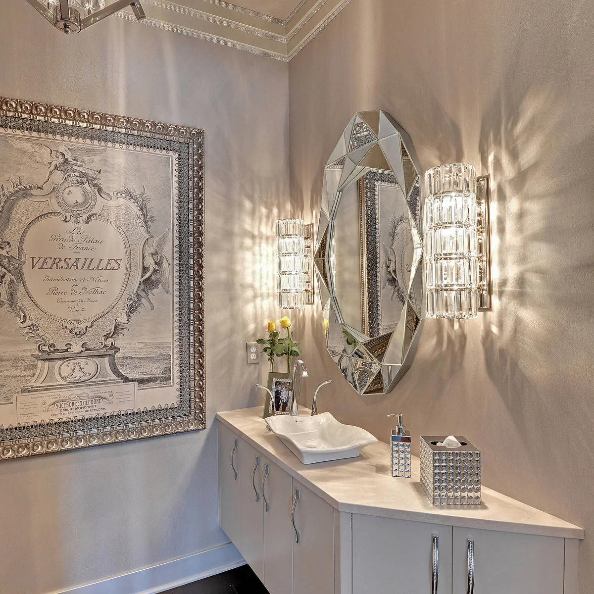 Large decorative typographic print beside a faceted mirror and sparkling wall lights
