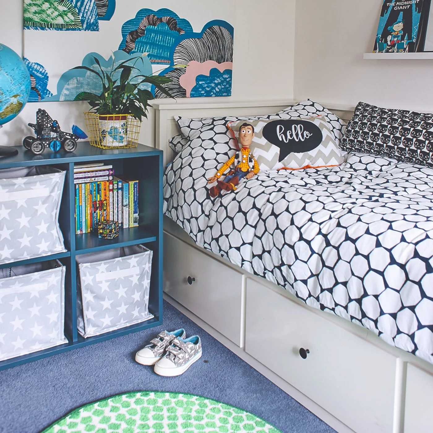 Blue cube shelf beside a bed with star-patterned fabric bins and one opening of upright books