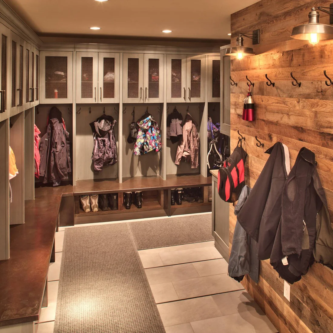 A timber hook wall with metal lamps beside built in benches and mesh front upper cupboards
