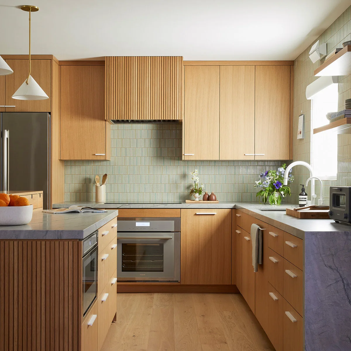 Compact wood-fronted kitchen with green vertical tile and a ribbed hood surround