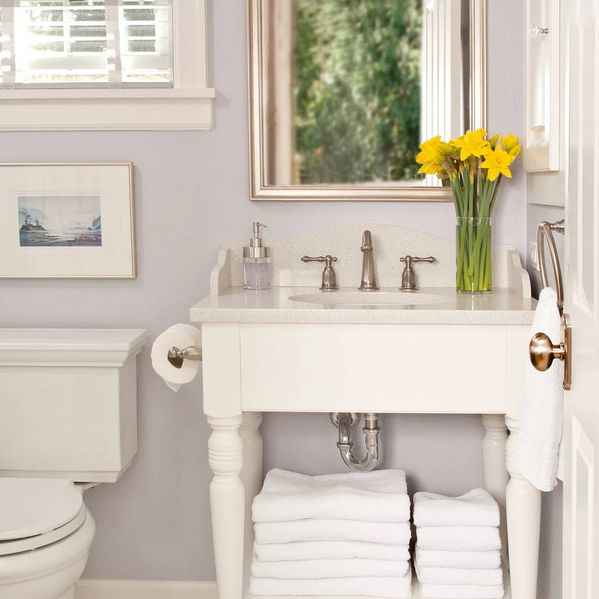 Small white washstand with folded towels on its lower shelf