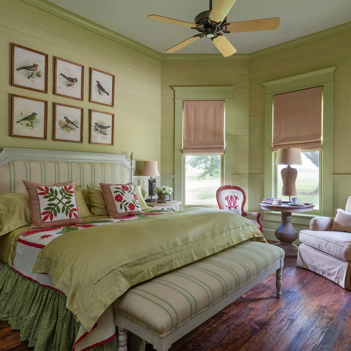 Pale green bedroom with bird prints, floral pillows, pink accents and a striped upholstered bench