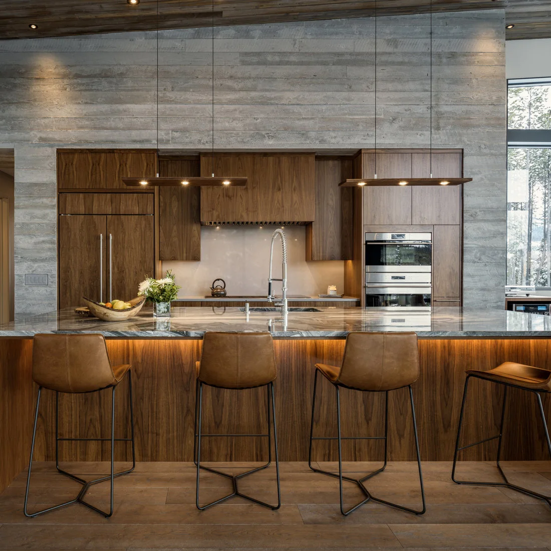 Flat wood kitchen fronts set within a textured gray wall behind a long illuminated island