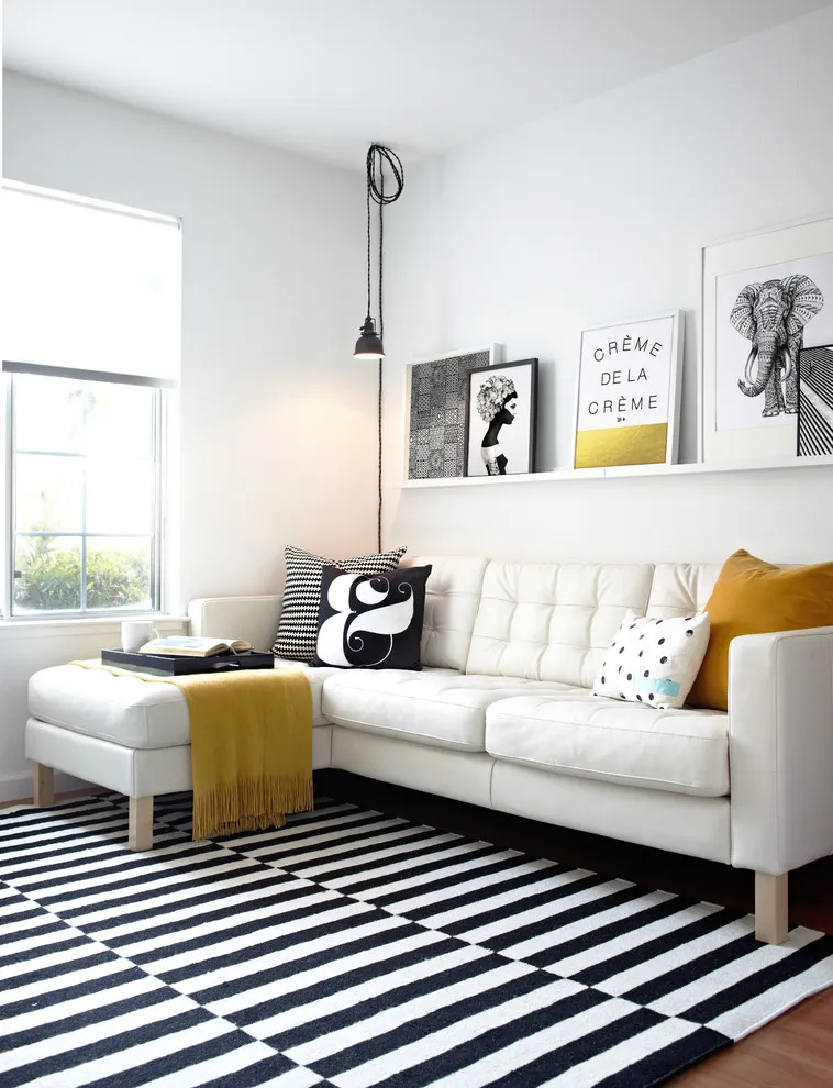A narrow picture ledge holds framed art above a pale sofa
