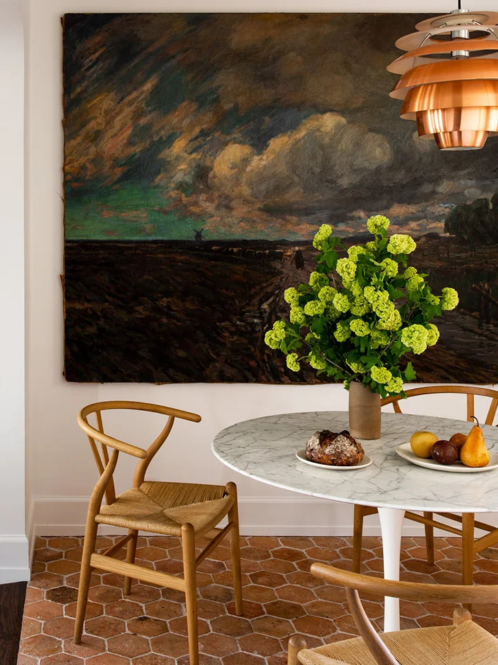 Warm hexagonal floor tiles remain visible below a round pale table and timber dining chairs.