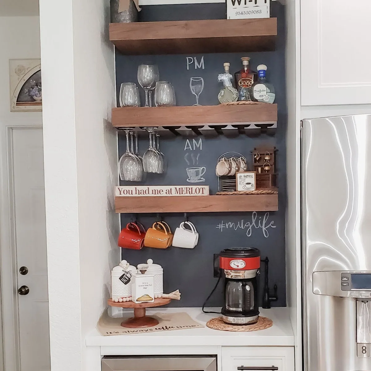 Slim coffee station beside a refrigerator with hanging mugs and chalkboard-backed wooden shelves
