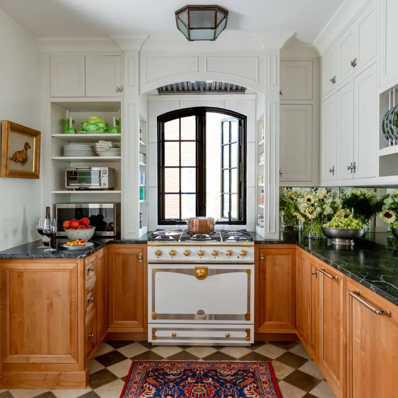 Warm honey-colored lower cupboards contrast with white upper cabinets, dark green counters and a cream range in a small kitchen.