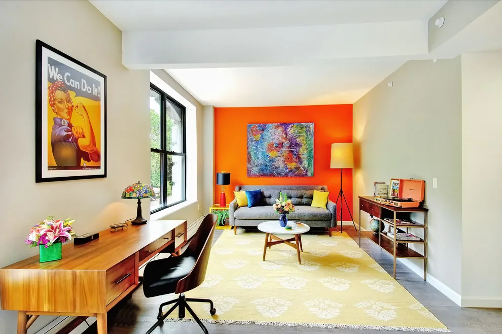 An orange wall frames a small seating area at the end of a long, bright room