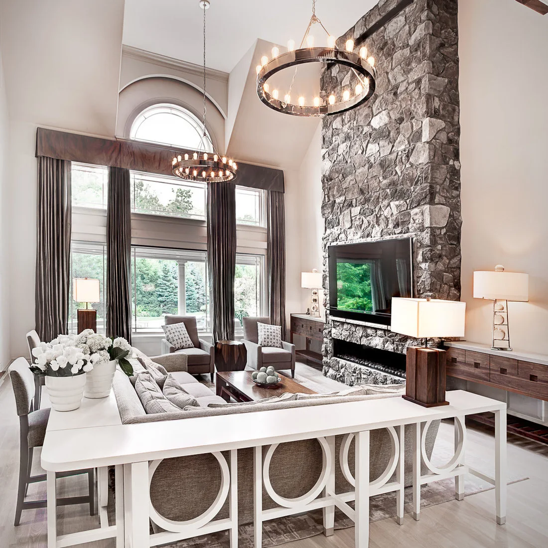 White consoles with circular open panels surround the back and end of a gray sofa.