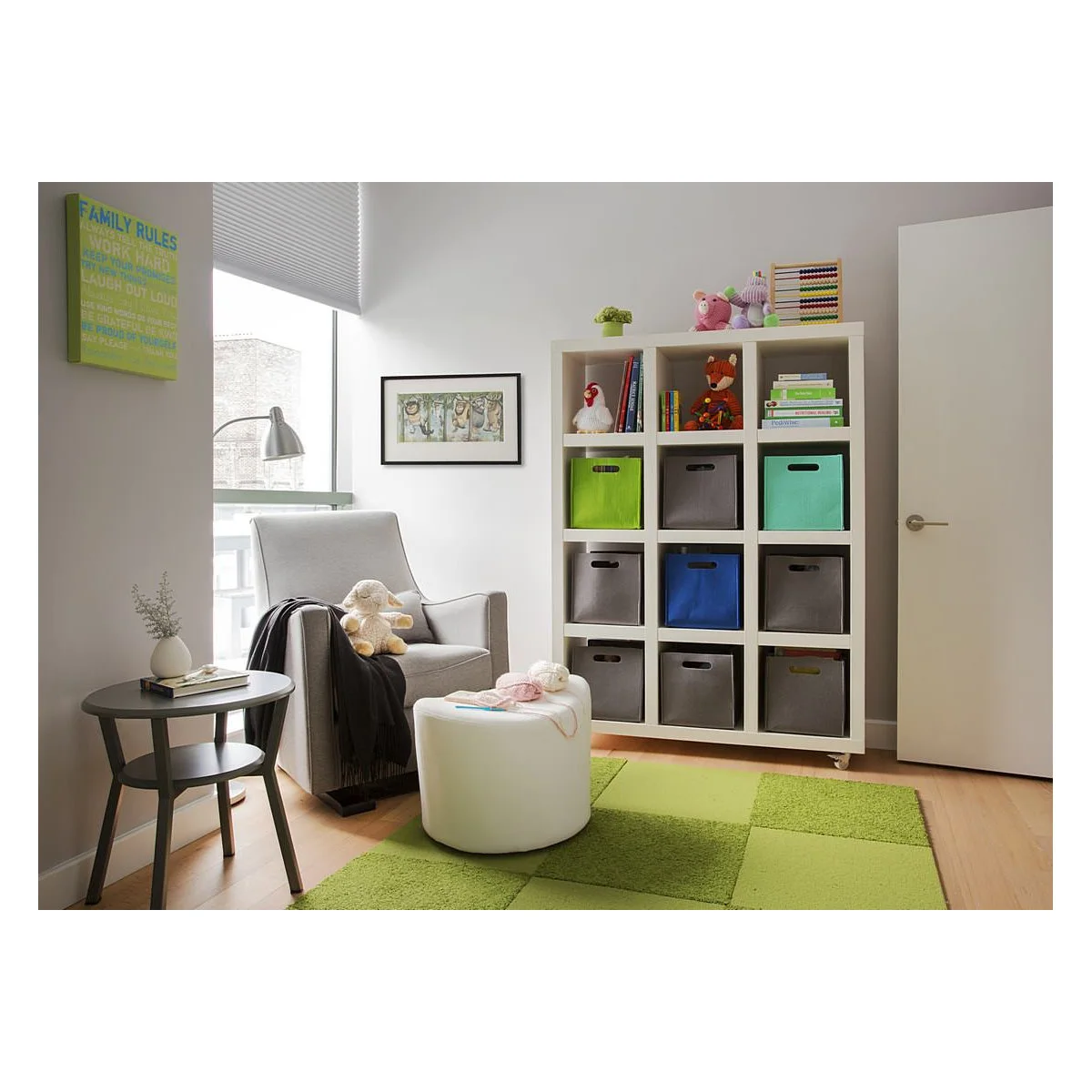 Nursery seating corner beside a tall white cubby unit with green, grey and blue fabric bins