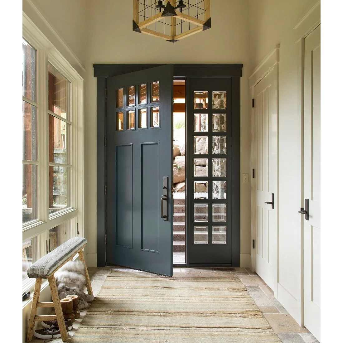 A narrow cushioned wooden bench and broad pale rug beside a dark paneled entrance door
