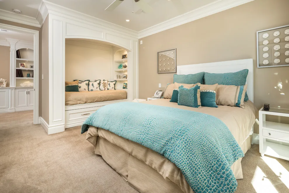 A turquoise cover sits on a bed in a warm beige room with pale furniture